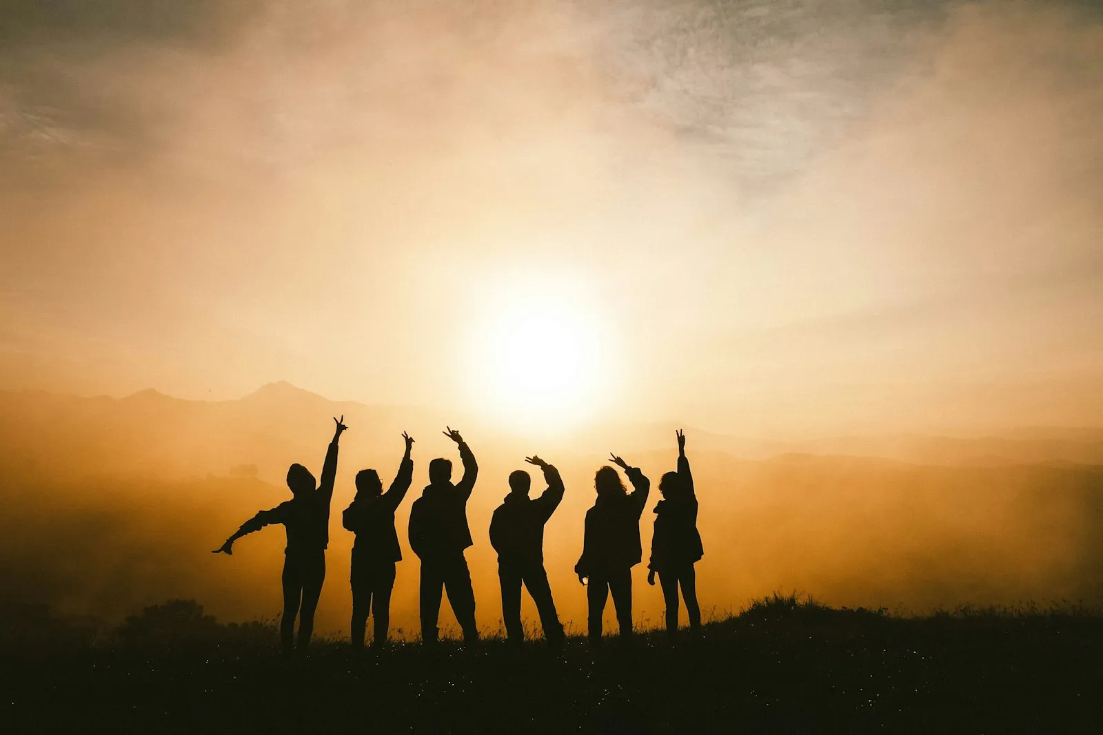 Friends silhouetted on a mountain at sunset