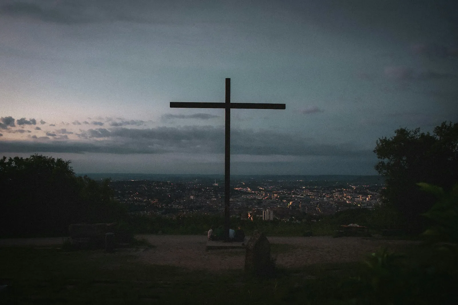 Wooden cross on a grassy hill against the sky