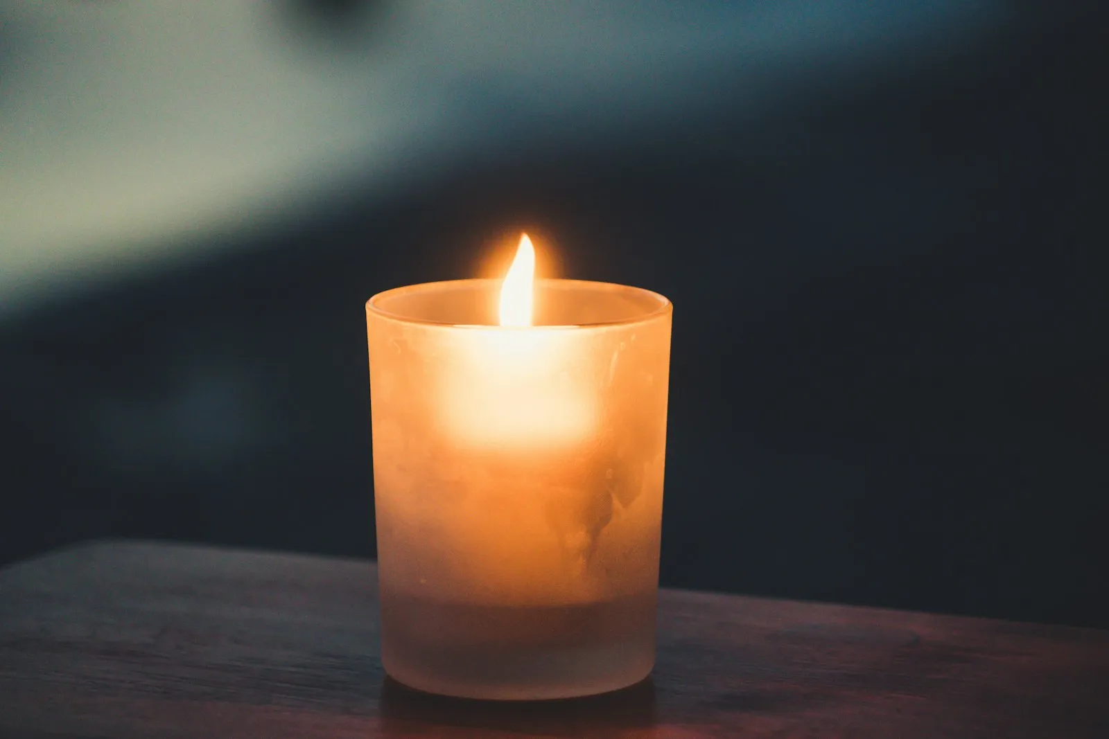 Single candle glowing warmly on a surface