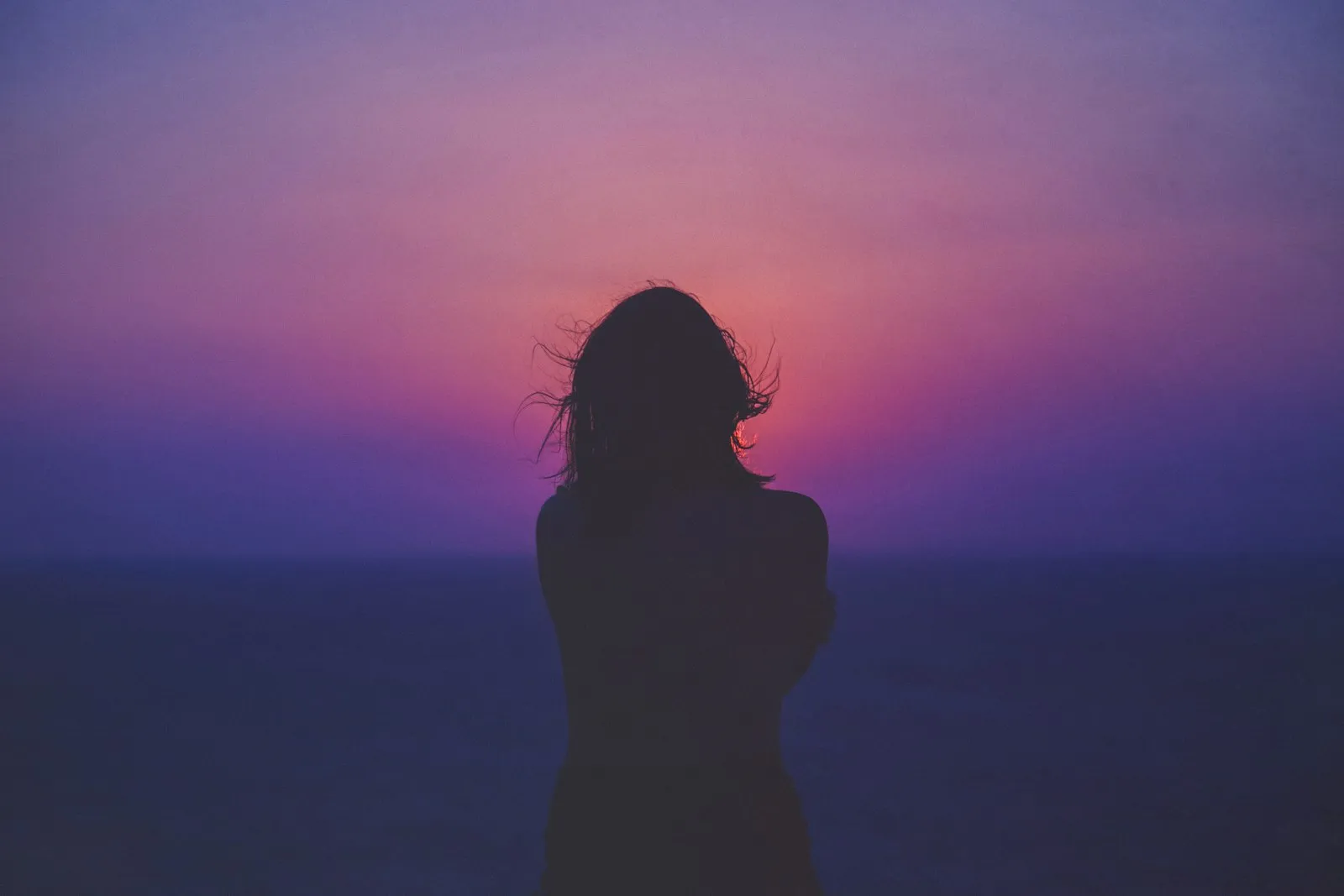 Woman silhouetted against a glowing sunrise
